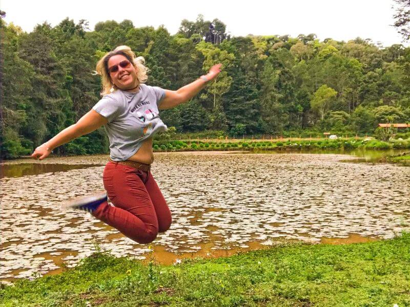 Menina pulando em frente a lago no hotel São Cristóvão em Campos do Jordão