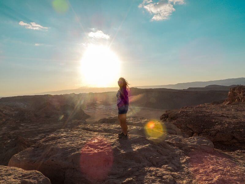 Pôr do sol no Deserto do Atacama com menina e formações e rochosas