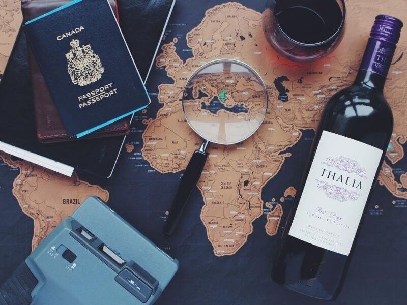 Passaporte, vinho, lupa, camera em cima de mapa