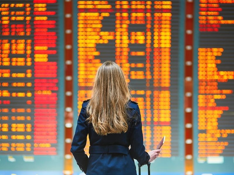 Voo cancelado o que fazer - Perrengue de viagem - Moça olhando painel aeroporto